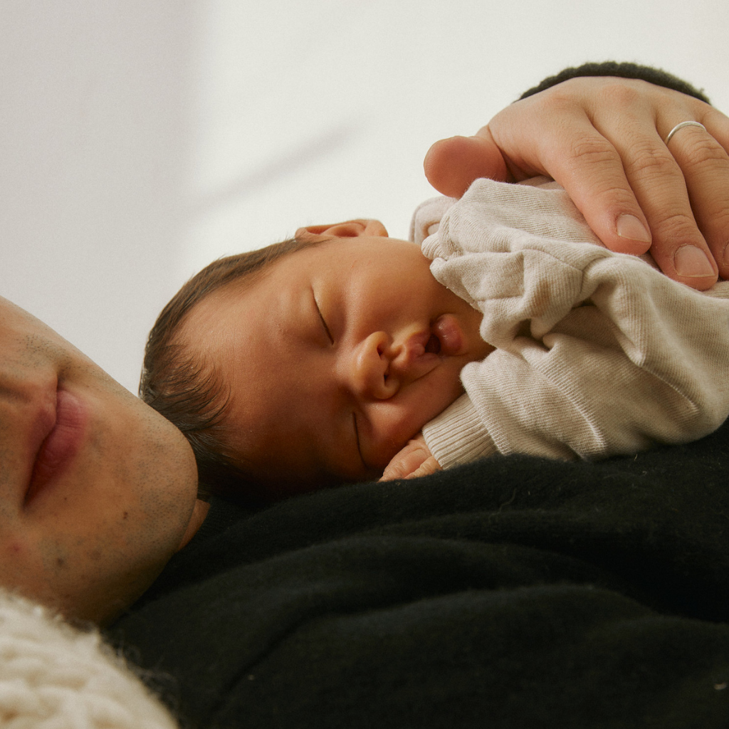 A very small baby asleep on a man's chest.