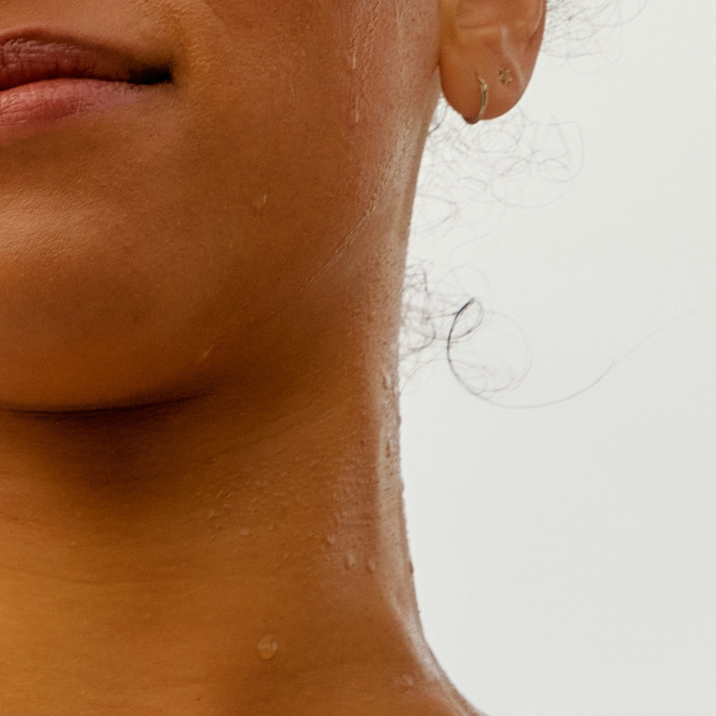 Close up of a persons neck and lower face. With beads of sweat or water.