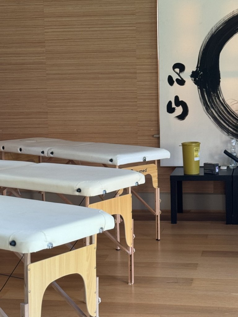 the Get Well Clinics at zen yoga with three treatment tables set up for clinic and a black and white zen calligraphy painting on the wall behind the tables.