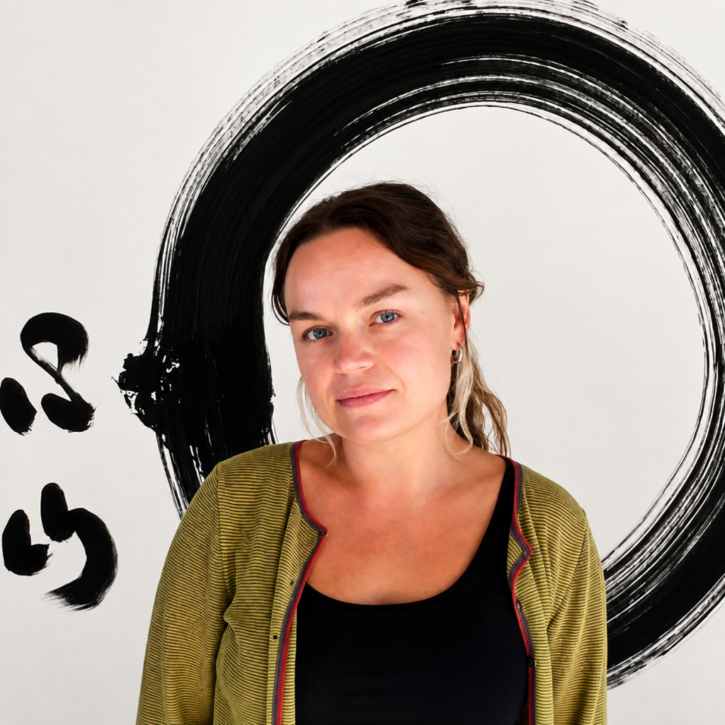 Portrait image of Minnie Casey wearing a black top and green cardigan against a white painting with a black circular brushstroke